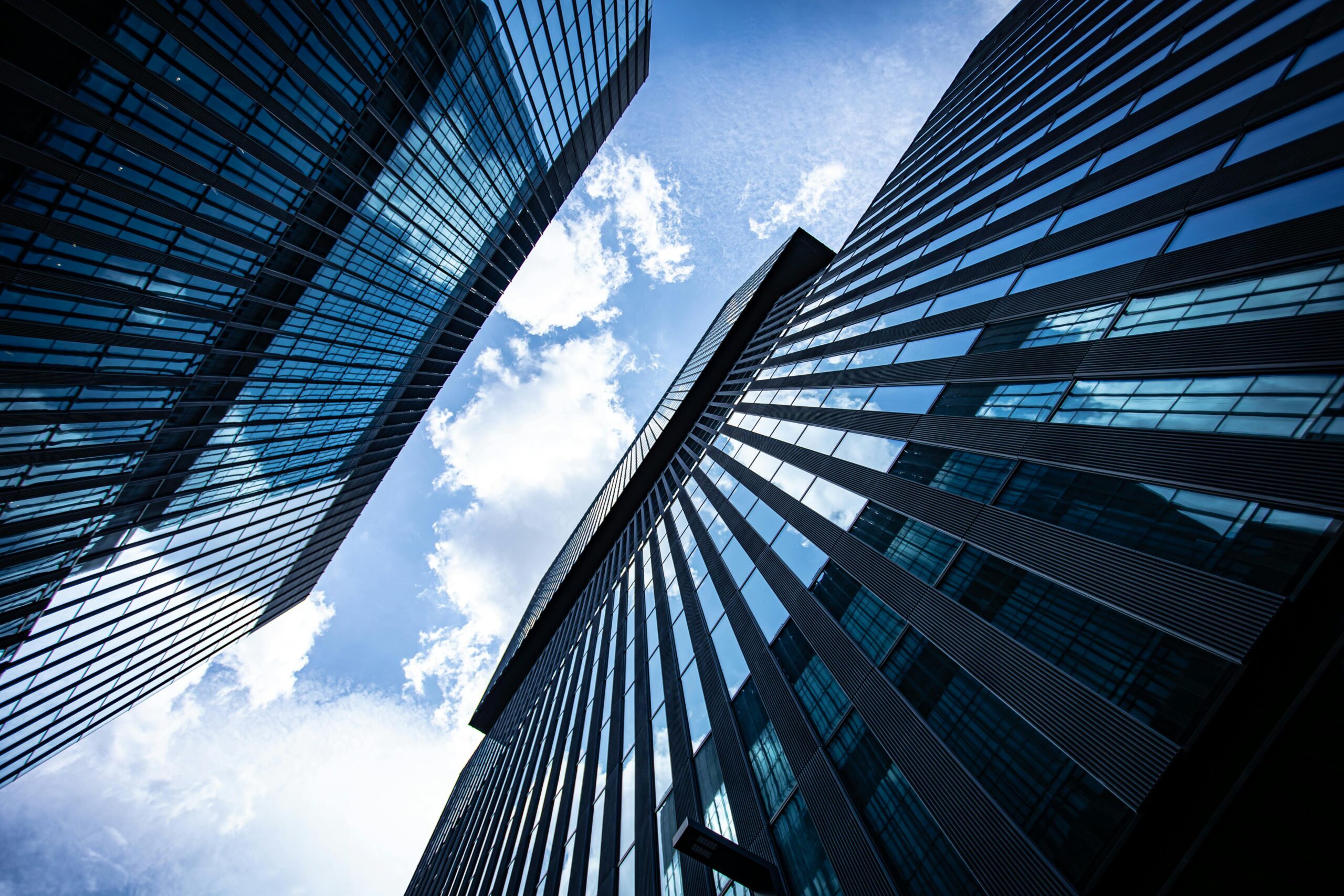 Dynamic view of modern skyscraper exteriors against a bright blue sky, showcasing urban architecture.
